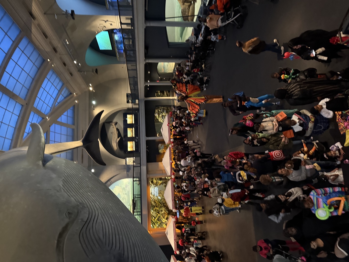 Families in Halloween costumes gather beneath the blue whale at the American Museum of Natural History