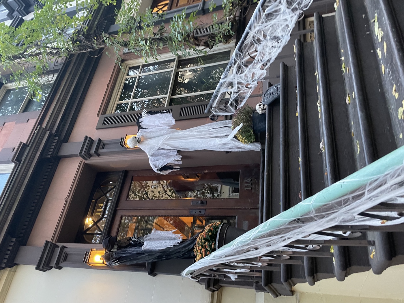 White ghosts and cobwebs decorate the railings and doorway of a New York brownstone